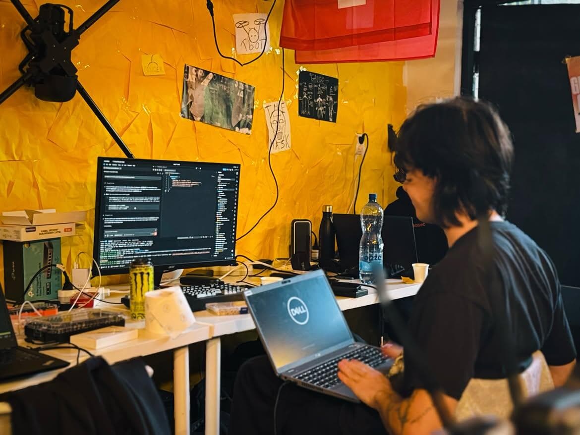 A participant coding on a laptop in the garage, against a yellow wall