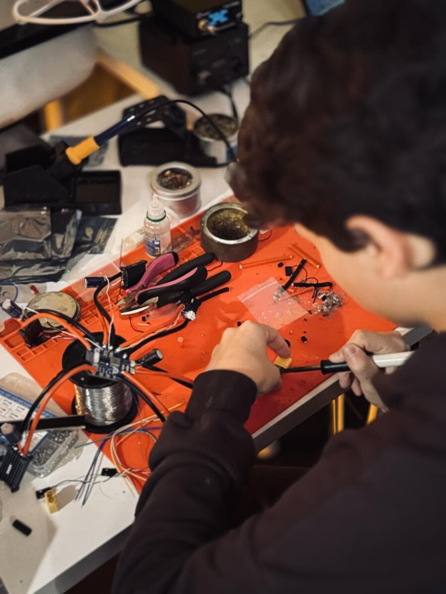 A participant soldering wires over an orange mat