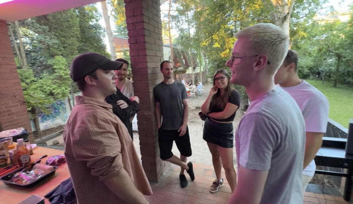A group talking on the porch, with the garden behind them