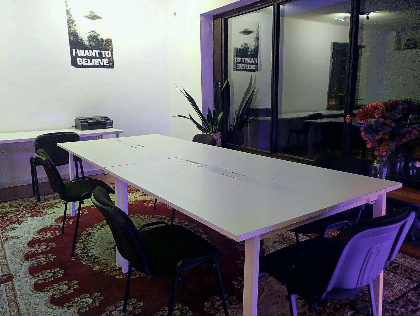 The shared table and chairs in the coworking room, with a printer on the side desk